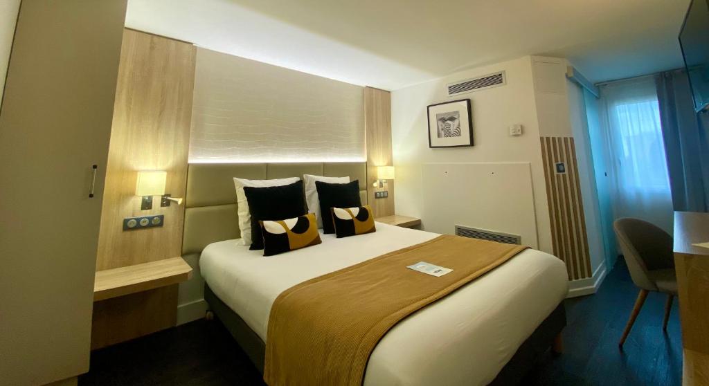 um quarto de hotel com uma cama grande com almofadas em Kyriad Beaune em Beaune
