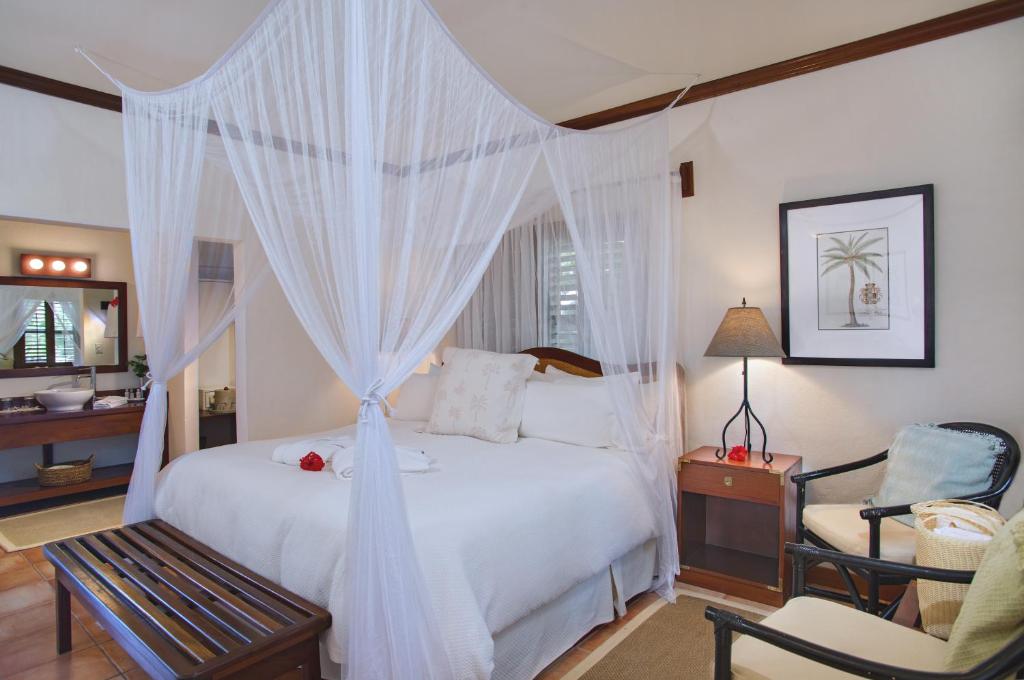 a bedroom with a white bed and a chair at Victoria House Resort & Spa in San Pedro