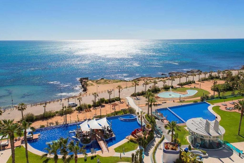 an aerial view of a resort with a pool and the ocean at Apartament Sea Senses Summer in Punta Prima