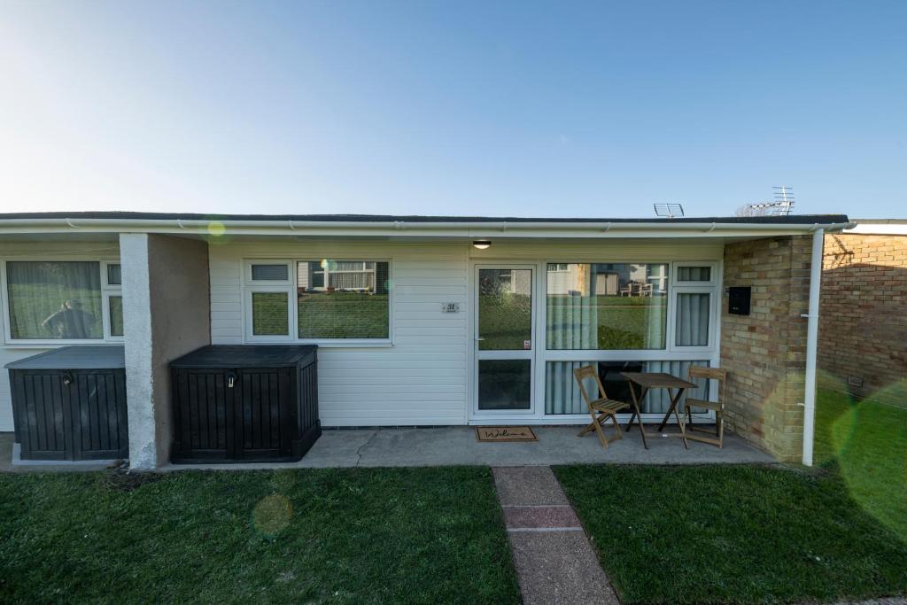 a house with a patio with a table and chairs at Find peace in a chalet by the beach in Kessingland