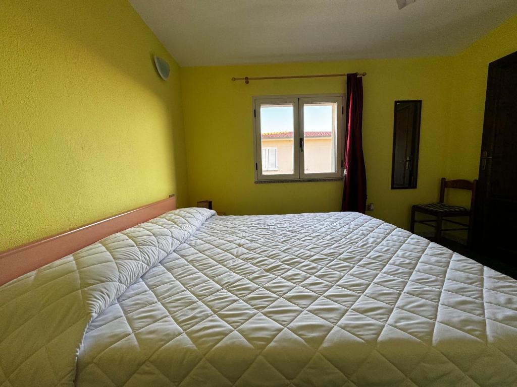 um quarto com uma grande cama branca e uma janela em Berchida 1 em La Caletta