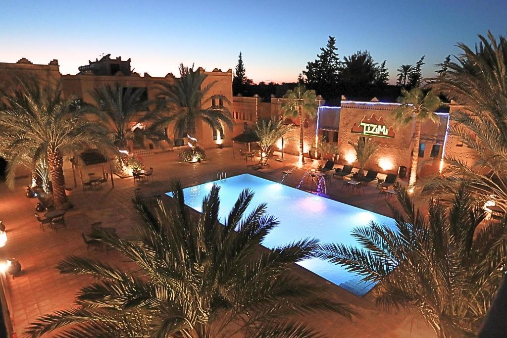 uma vista sobre uma piscina num pátio com palmeiras em Kasbah Tizimi em Arfoud