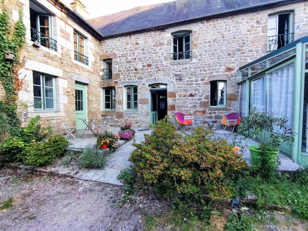 una casa de piedra con un jardín delante de ella en Le cheval blanc, en Carrouges