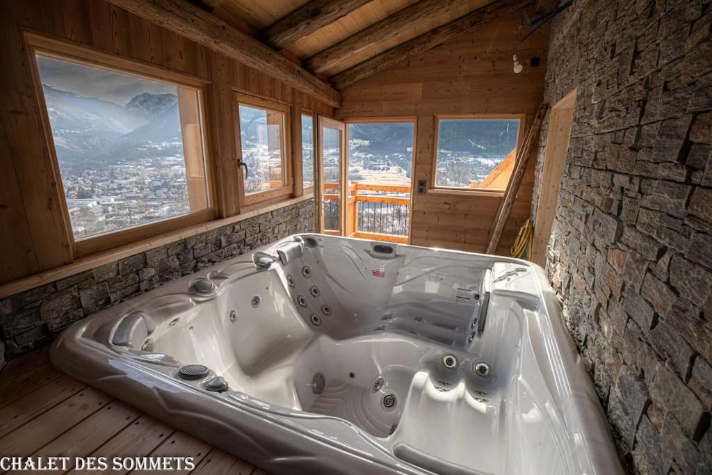 bañera grande en una habitación con ventanas en Le Chalet des Sommets à Briançon, en Puy-Saint-Pierre