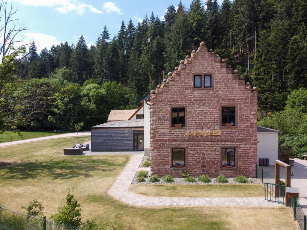 a brick house in the middle of a yard at Les Jardins du Nideck in Oberhaslach