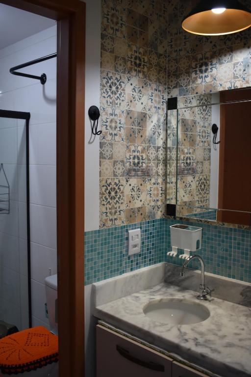ein Bad mit einem Waschbecken und einem Spiegel in der Unterkunft Apartamento próximo a Canção Nova in Cachoeira Paulista