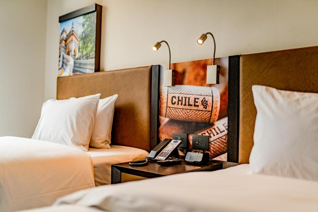 Hampton By Hilton Santiago Las Condes في سانتياغو: غرفة فندقية بسريرين وطاولة مع هاتف