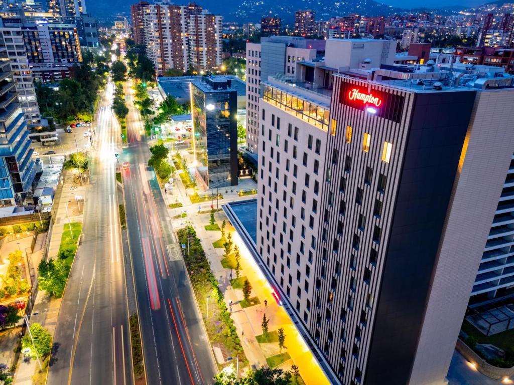 un perfil urbano por la noche con un alto edificio blanco en Hampton By Hilton Santiago Las Condes, en Santiago