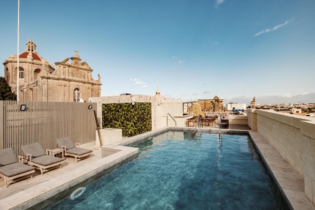 Hal Ghaxiak的住宿－Palazzo Castagna Boutique Hotel，一座带椅子的建筑屋顶上的游泳池