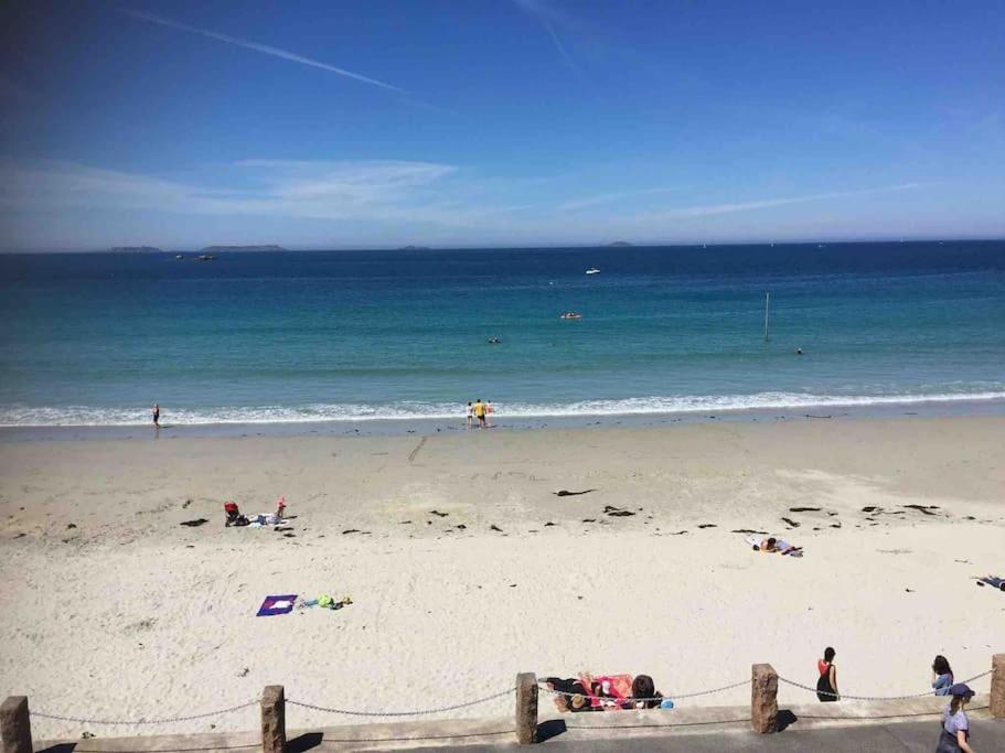 - une plage avec des gens sur le sable et l'océan dans l'établissement TRESTRIGNEL MAGNIFIQUE VUE MER. Studio à PERROS-GU, à Perros-Guirec