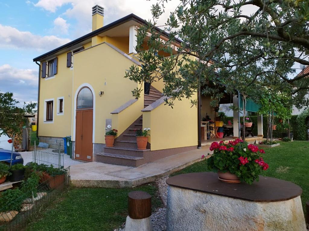 a small yellow house with flowers in a yard at Nika's Sea View Oasis in Seget