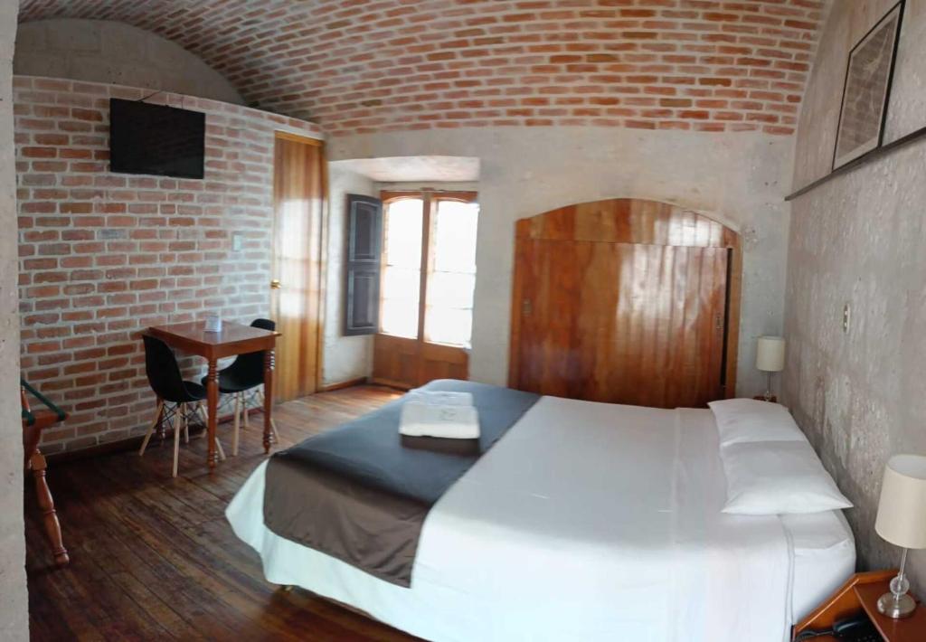 a bedroom with a white bed and a brick wall at La Casa de Margott in Arequipa