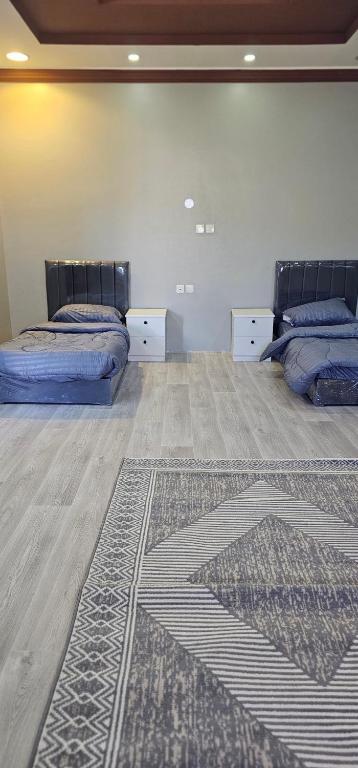 two beds in a room with a rug on the floor at غرفة خاصة in AlUla