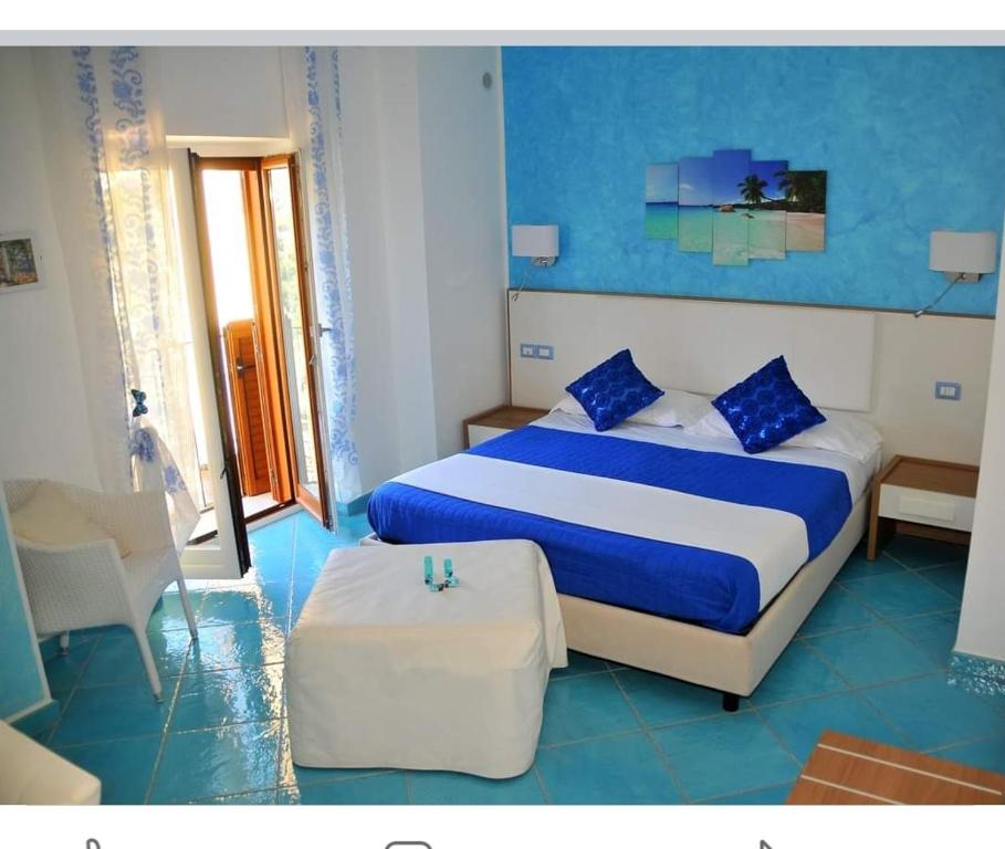 - une chambre avec un lit bleu et blanc et une chaise dans l'établissement Le Perle d'Italia, à Ravello