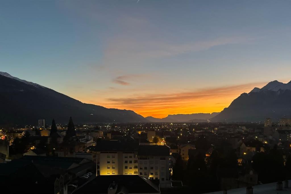 un coucher de soleil sur une ville avec des montagnes en arrière-plan dans l'établissement Appartement 4 couchages centre-ville, à Albertville
