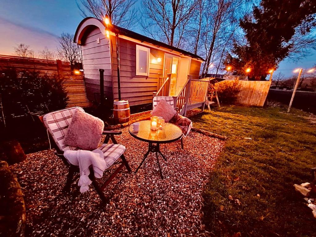 two chairs and a table in front of a house at Whiskers and Woods Shepherd Hut 