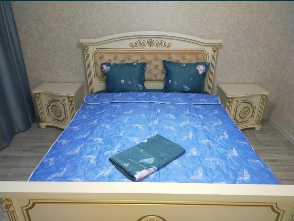 een bed met een blauw dekbed en een boek erop bij Уютная 3-х комнатная квартира in Oral