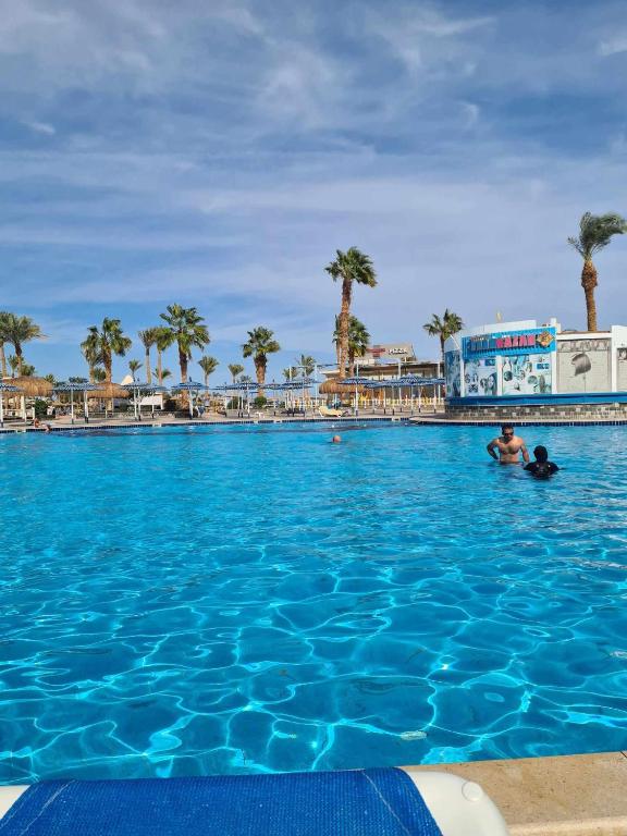a large swimming pool with palm trees in the background at شاليه مميز جدا فندق ميراج شاطئ كبير in Hurghada