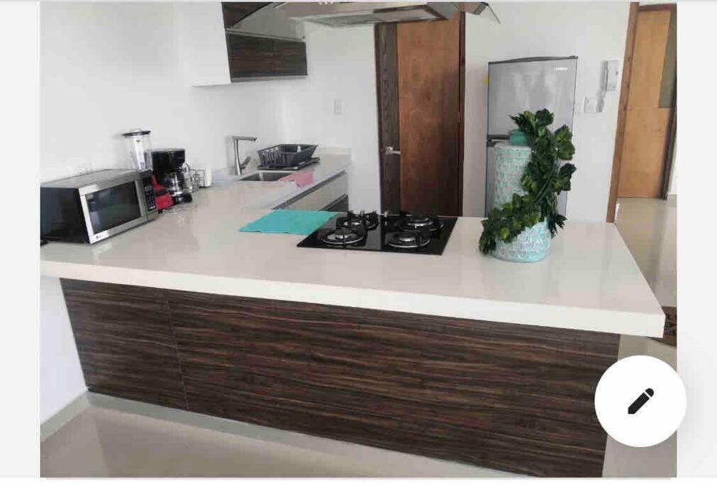 a kitchen with a counter with a stove and a microwave at Departamento en lomas de angelopolis, Isla blanca in Lomas de Angelopolis