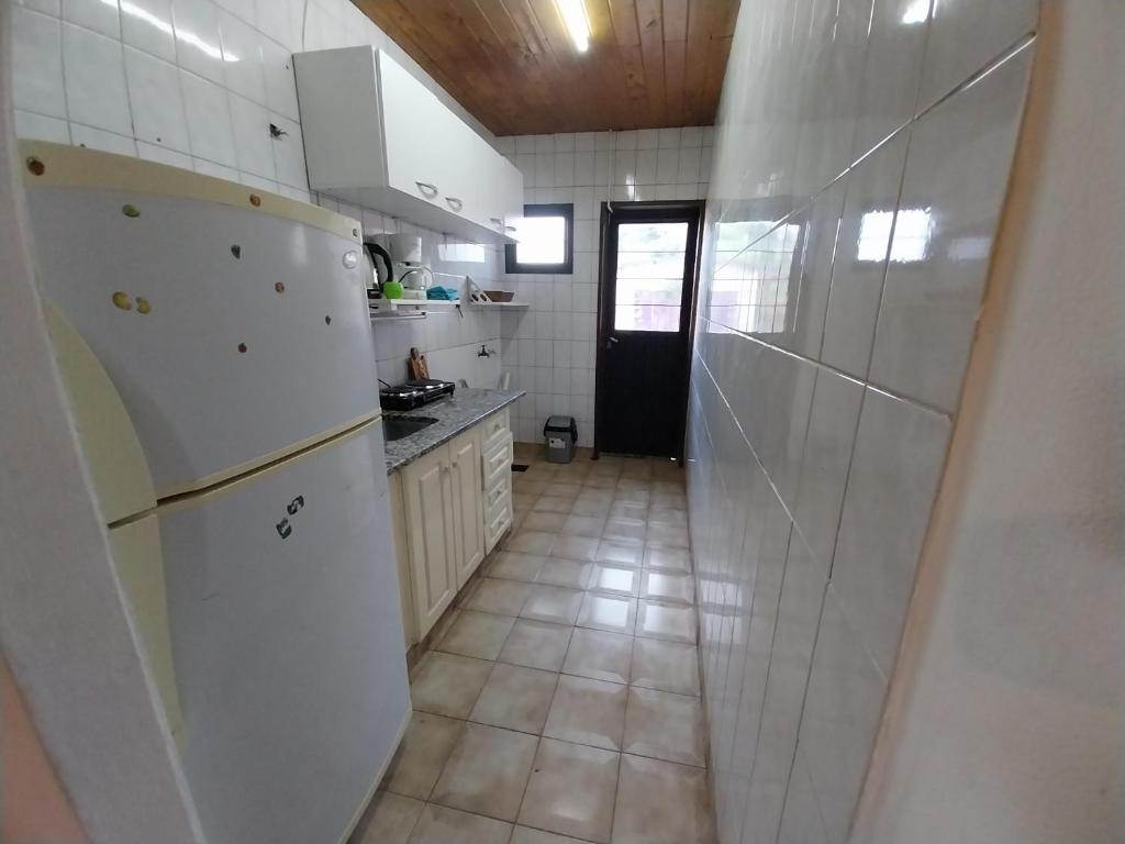 a kitchen with a white refrigerator and a tile floor at Casita Mutisia in Neuquén