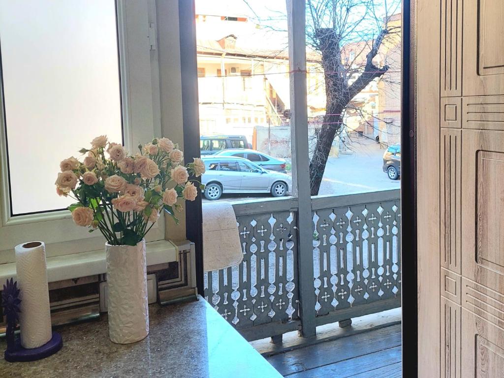 Un jarrón de flores en un balcón con un coche fuera en Dali's Royal Apartment, en Tiflis