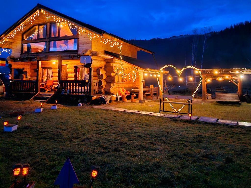 eine Blockhütte mit Weihnachtslichtern im Hof in der Unterkunft La Căsuță in Vatra Dornei