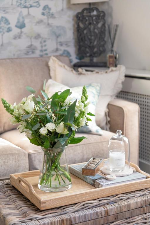 a vase of flowers on a table in front of a couch at Brunswick Cottage, Penrith, The Lake District in Penrith