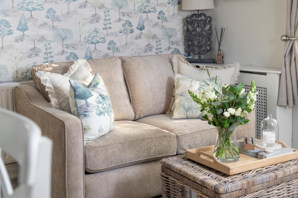 a living room with a couch and a table with a vase of flowers at Brunswick Cottage in Penrith