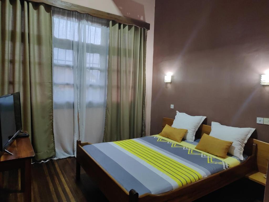 a bedroom with a bed with a window and a television at Hôtel Diamant Antsirabe in Antsirabe