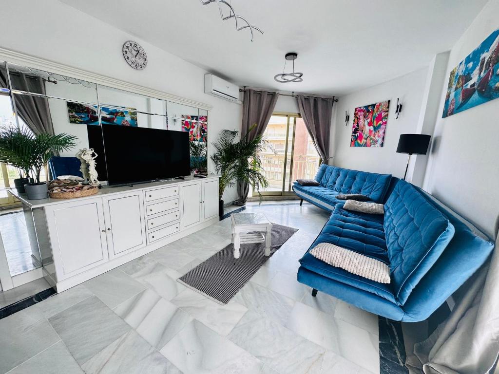 Playa Dona Sofia Bella في فوينخيرولا: غرفة معيشة مع أريكة زرقاء وتلفزيون