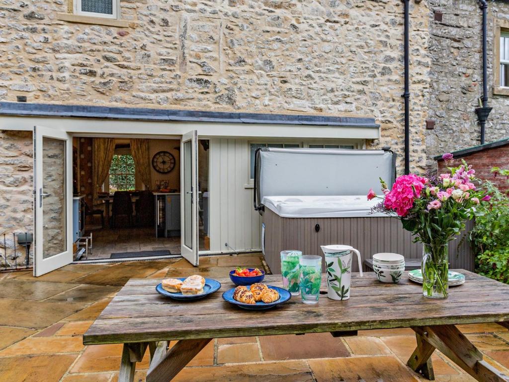 einen Holztisch mit Essen und Blumen auf einer Terrasse in der Unterkunft 3 Bed in Settle 76650 in Stainforth
