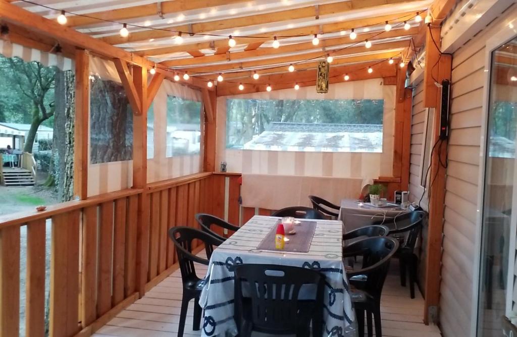 eine abgeschirmte Veranda mit einem Tisch, Stühlen und Lampen in der Unterkunft Mobil home Aventura 6-8 personnes tout confort in Saint-Brevin-les-Pins