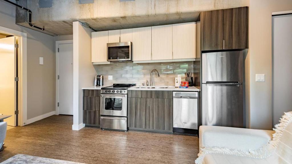 a kitchen with stainless steel appliances and wooden cabinets at Landing - Modern Apartment with Amazing Amenities (ID5631X79) in Milwaukee