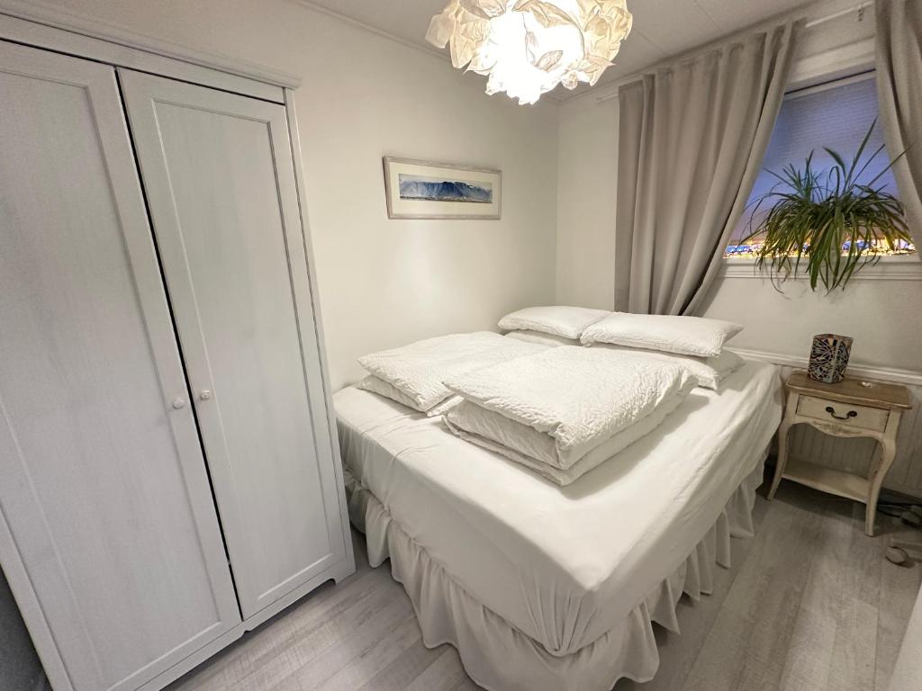 a bedroom with a bed with white sheets and a chandelier at Apartment in Reykjavikurvegur - Birta Rentals in Hafnarfjörður