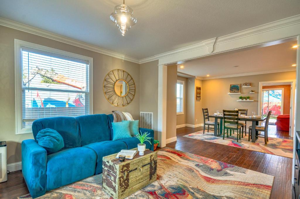 a living room with a blue couch and a dining room at Alberta Arts District Home with Private Hot Tub! in Portland