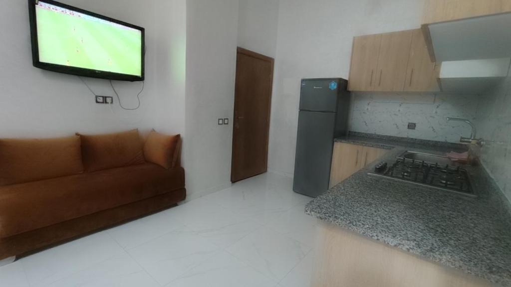 een woonkamer met een bank en een televisie aan de muur bij Ibraimo in Fès