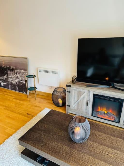a living room with a fireplace and a flat screen tv at Play Away Lodge in Basildon