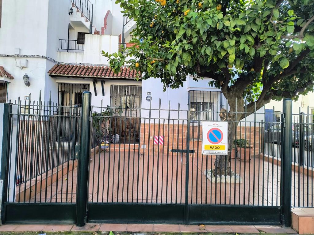 una cerca con un árbol delante de una casa en Casa El limonero en Sevilla