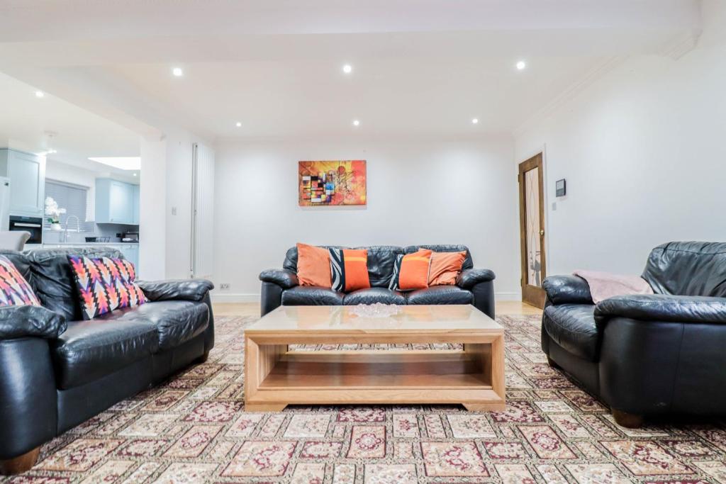 a living room with two leather couches and a coffee table at Luxurious 5 Bed Property! in Woodley