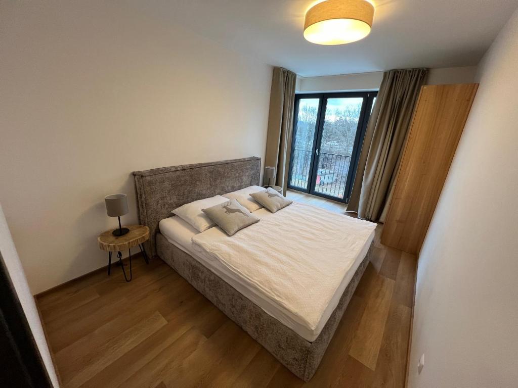 a bedroom with a large bed with a window at BlackDEER Apartment Liptov in Liptovský Mikuláš