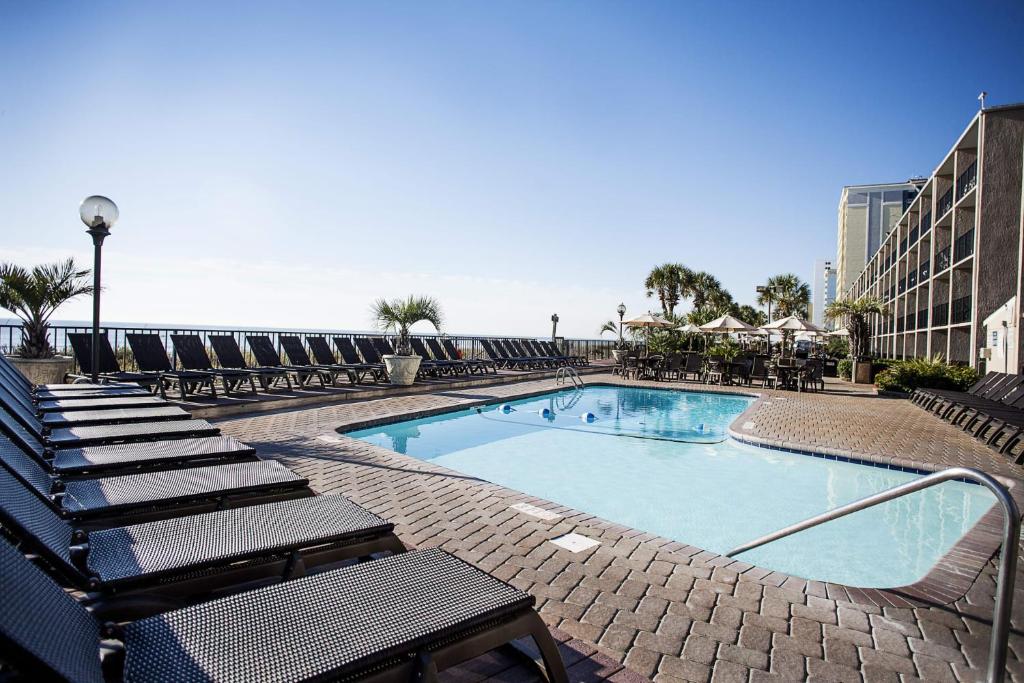 a swimming pool with chaise lounges and chairs at Indigo in Myrtle Beach