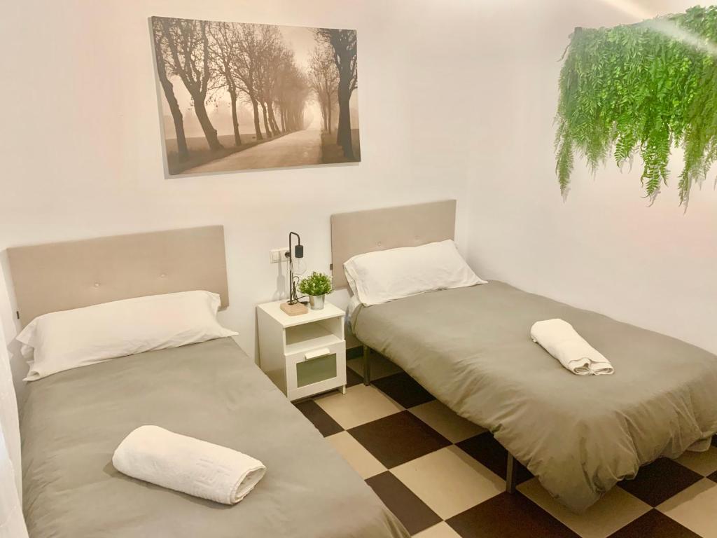 two twin beds in a room with a checkered floor at LOS ROSALES in Alcaracejos