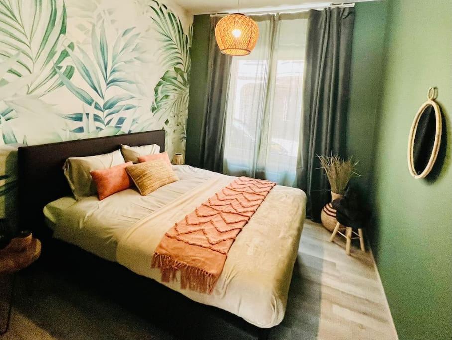 een slaapkamer met een groot bed met kussens erop bij Appartement tropical in Luik