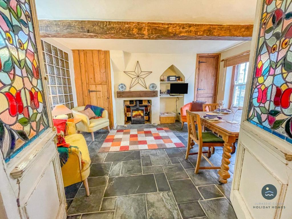 a living room with a table and a fireplace at Rope Cottage - traditional cottage close to town in Bridport