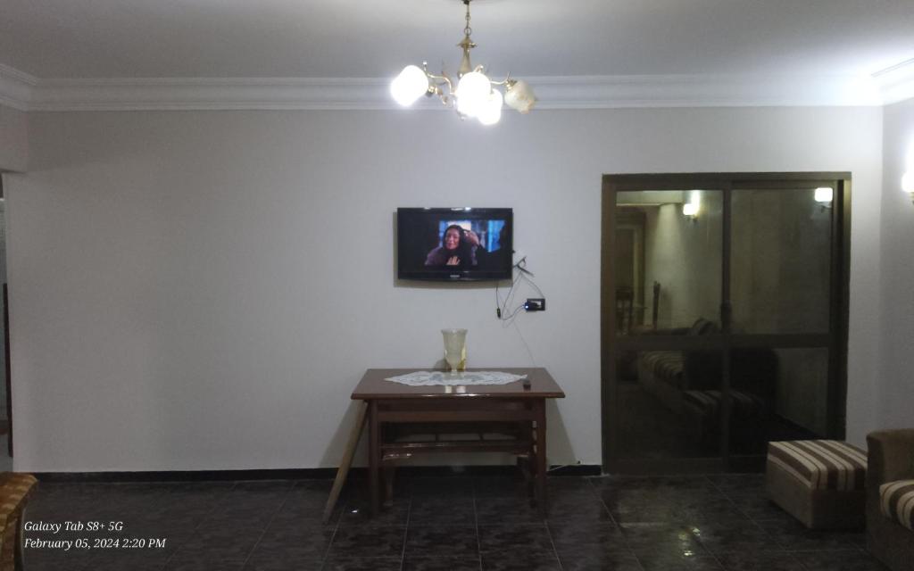 a living room with a table and a tv on the wall at Kerlos house in 6th Of October