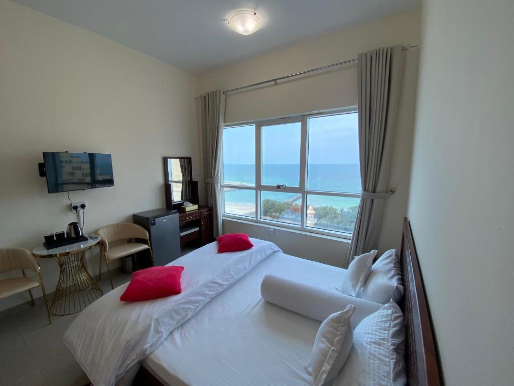 Un dormitorio con una cama con almohadas rojas y una ventana en Family rooms with beach view, en Ajman