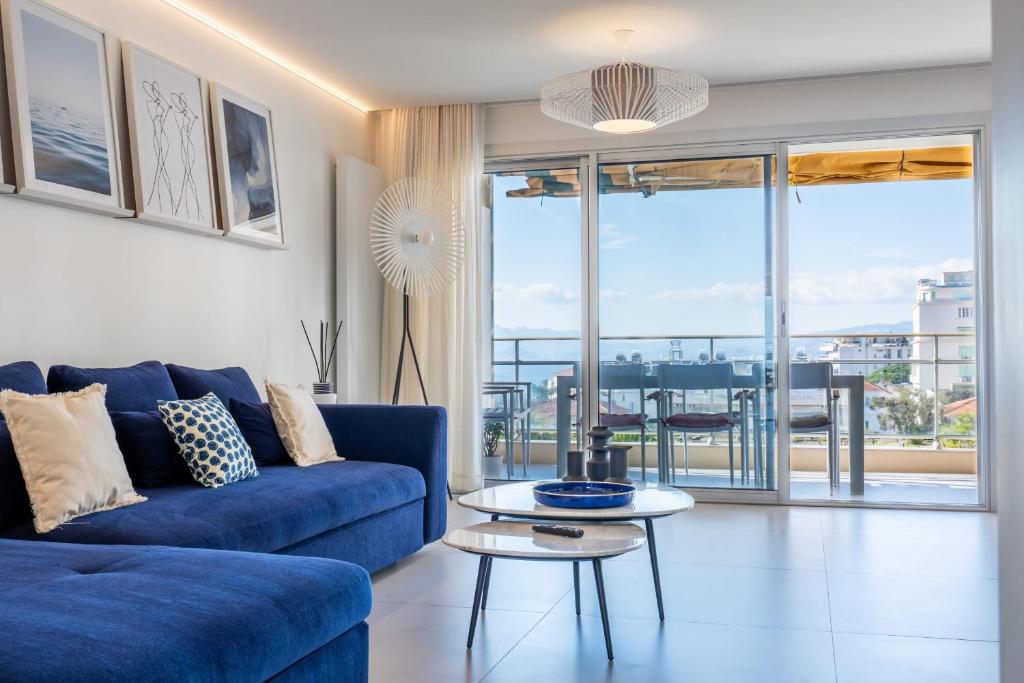 un salon avec un canapé bleu et une table dans l'établissement 3-bedroom apartment sea view terrace and parking, à Cannes