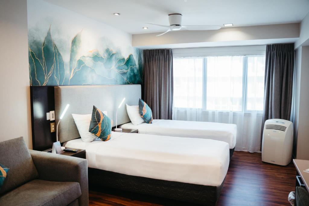 ein Hotelzimmer mit 2 Betten und einem Sofa in der Unterkunft Auckland City Hotel - Hobson St in Auckland
