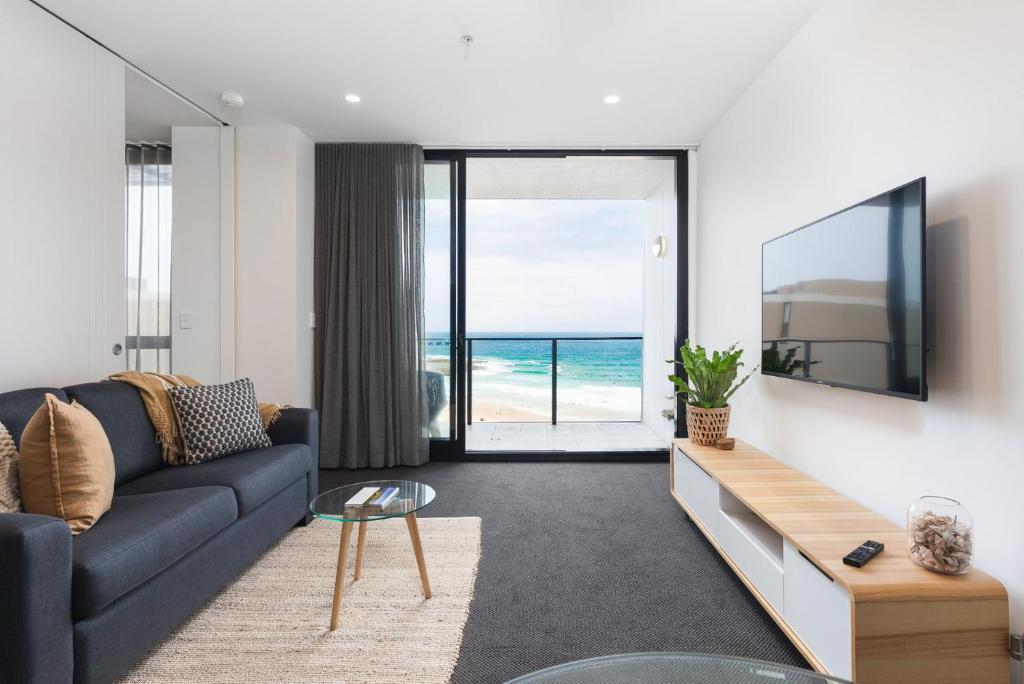 a living room with a couch and a tv and the ocean at The Aire in Newcastle