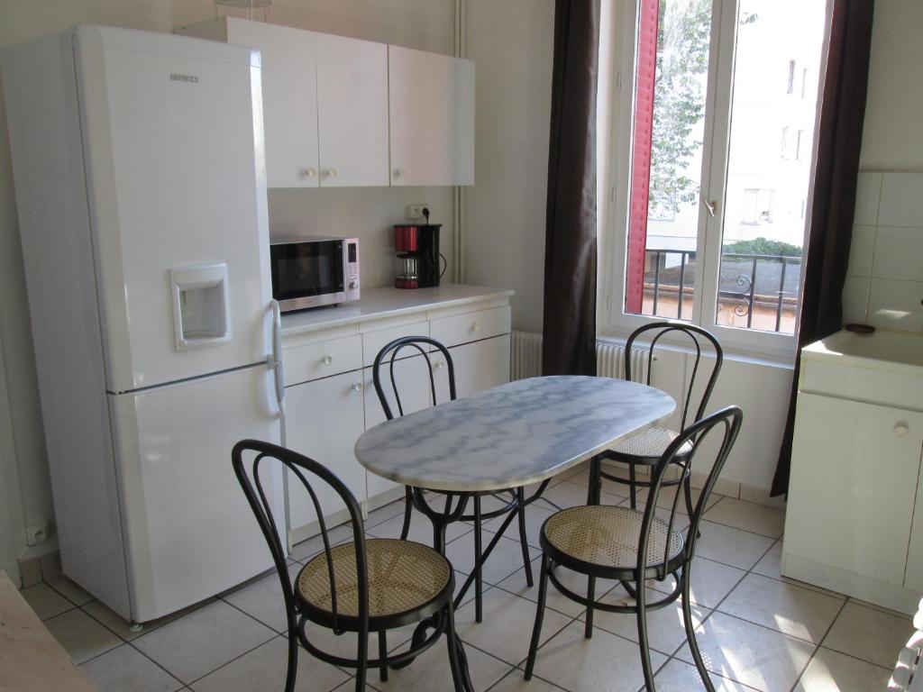 a kitchen with a table and chairs and a refrigerator at Santy. in Bron